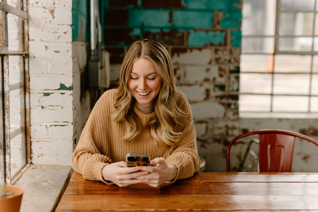 Woman using her smartphone at a table, photo by Brooke Cagle via Unsplash